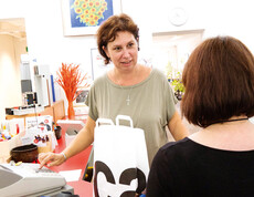 Mitarbeiterin bedient eine Kundin an der Kassa im carla Shop in Altach. Beide Frauen sind im mittleren Alter und tragen gemütliche, weite Kleidung. 