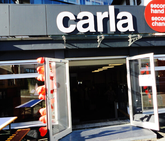 Außenansicht des carla-Shops in Dornbirn bei Tag. ie Außenfassade ist schicht in schwarz gehalten und viele Fenster ziert den etwa 10 Meter langen Shop. Der Schriftzug "carla" wurde über der Türe groß angebracht. 