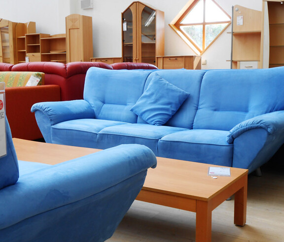 Eine blaue Couch steht in einem möbilierten Wohnzimmer. 